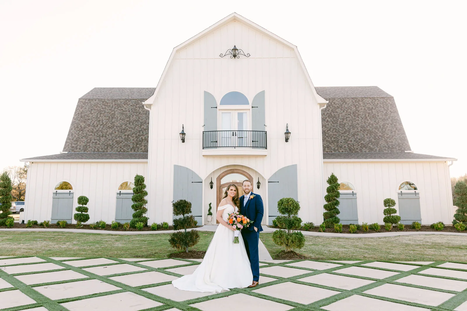Bride and groom in front of The French Farmhouse Venue main building.
