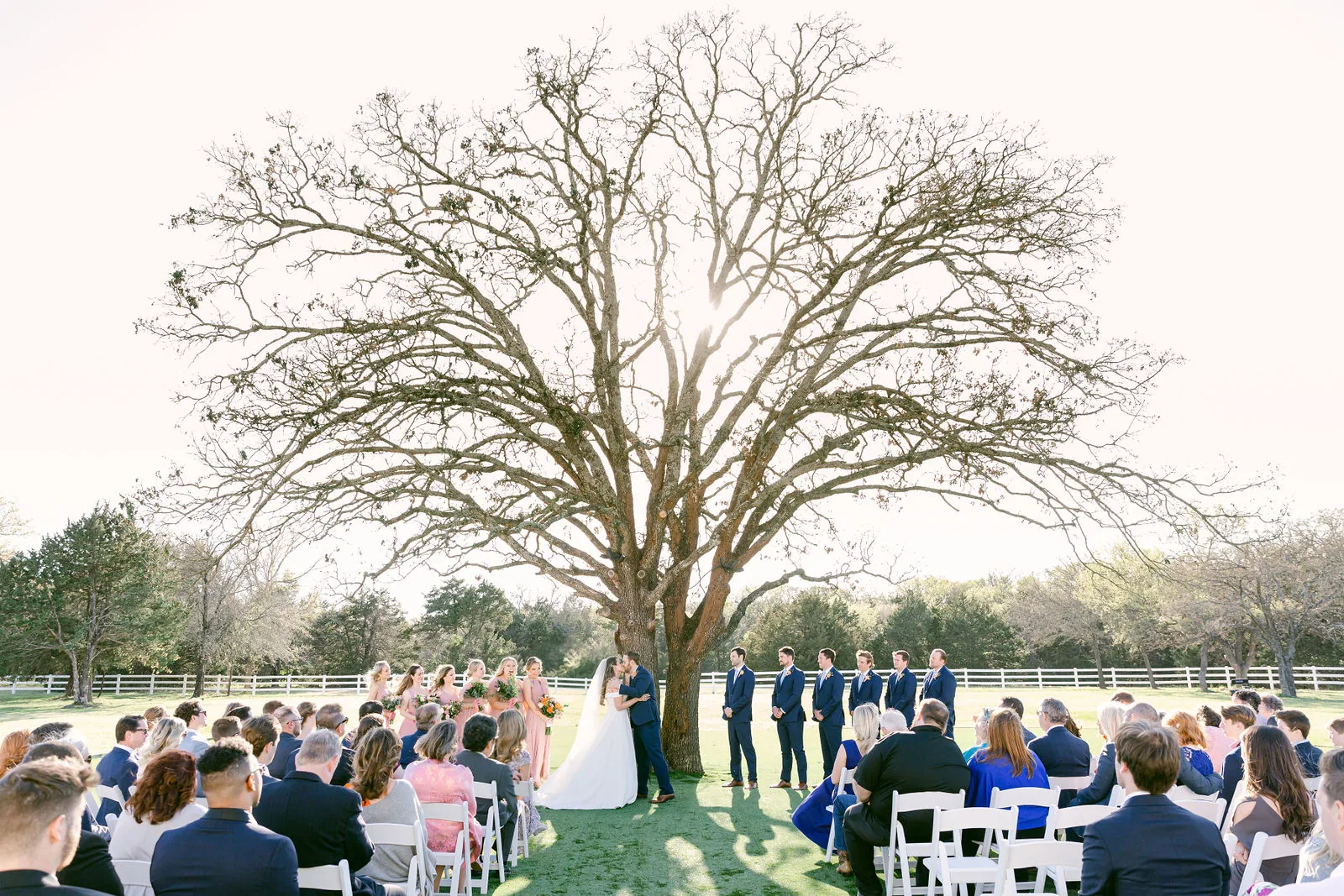 Bride and groom kissing beneath the outdoor ceremony tree at The French Farmhouse.