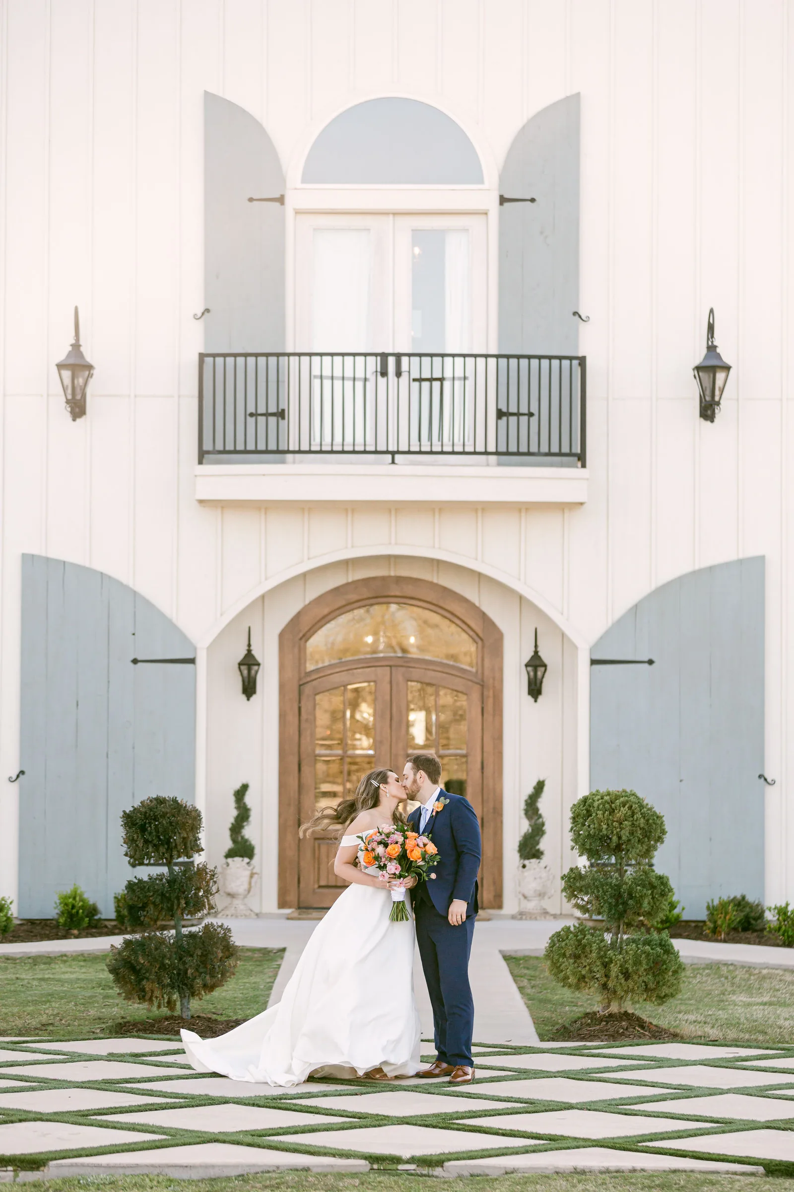 Bride and groom portrait beside the vintage car and main building.