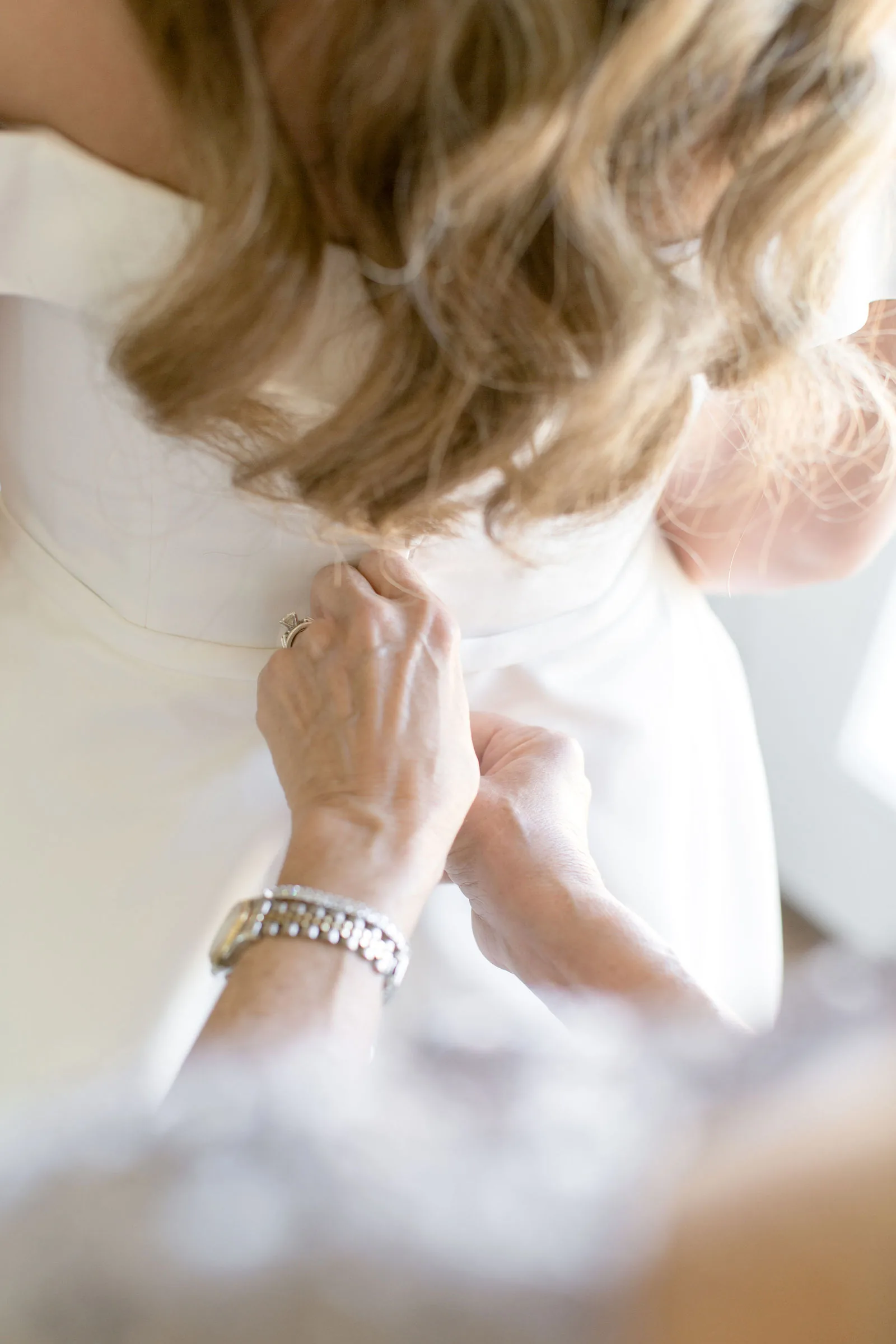Bride getting ready in soft window light inside the bridal suite.