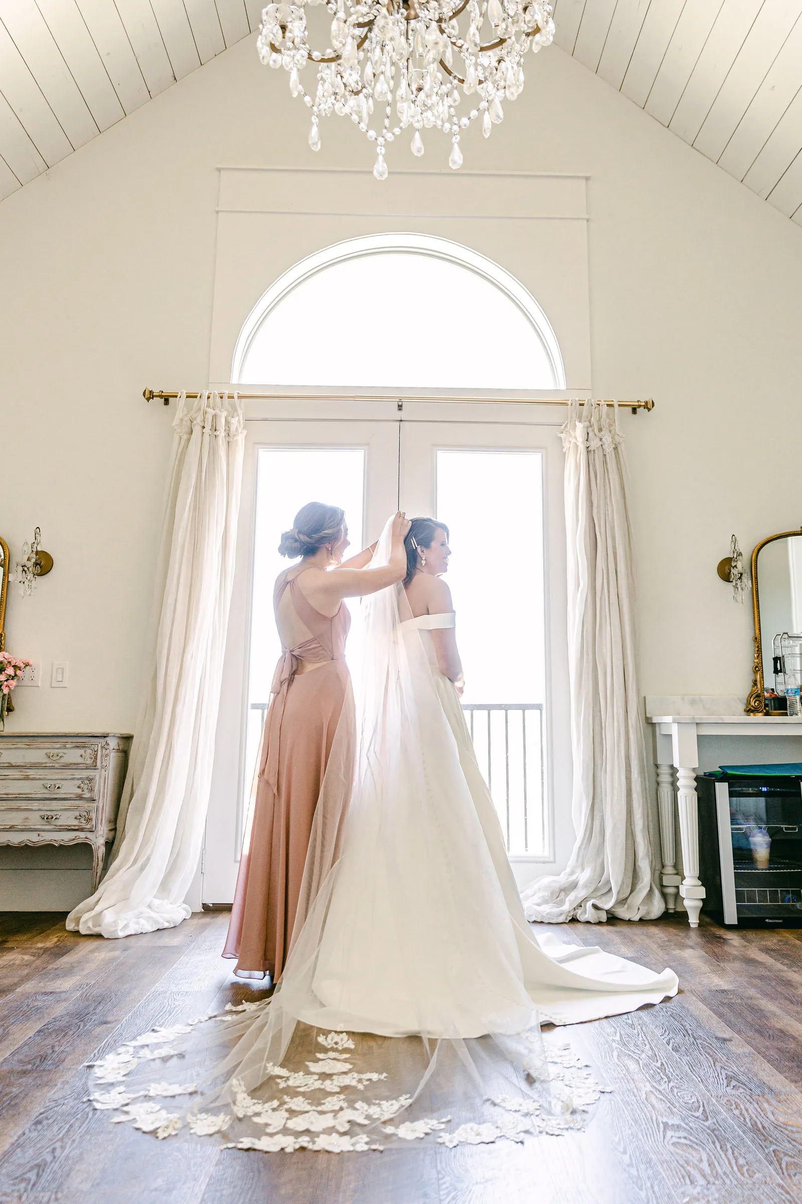 Bride getting ready near the large bridal-suite window.